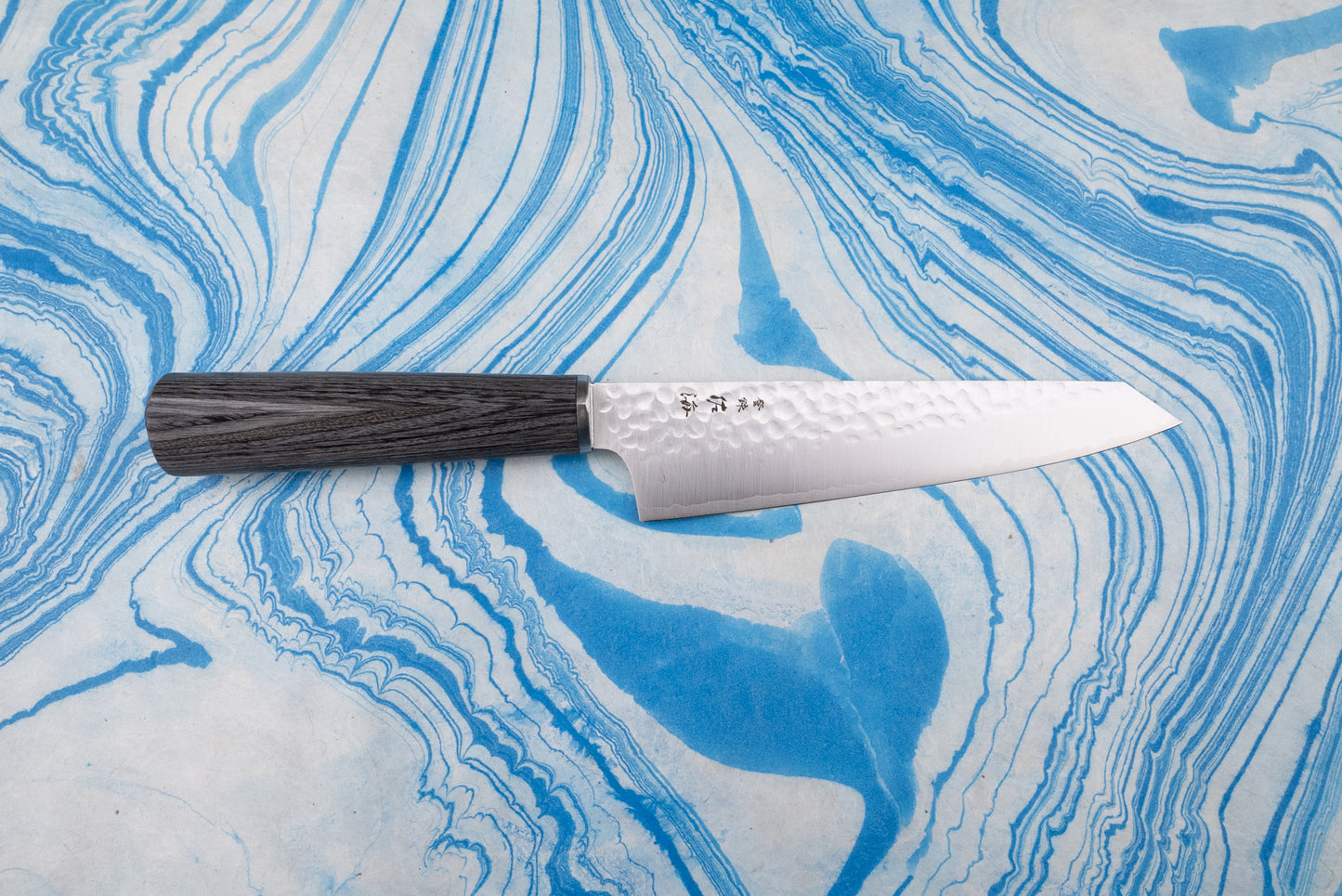 Touroku Sakai Gekka Ko-Bunka 150mm knife displaying a hammered stainless-steel blade and dark octagonal handle, set on a marbled surface, exemplifying Japanese craftsmanship and precision.