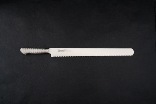 Brieto Pro Bread Knife 390mm M1148 with a long, thin serrated blade and hammered-metal handle, expertly designed for slicing bread without damaging its texture, displayed on a dark background.